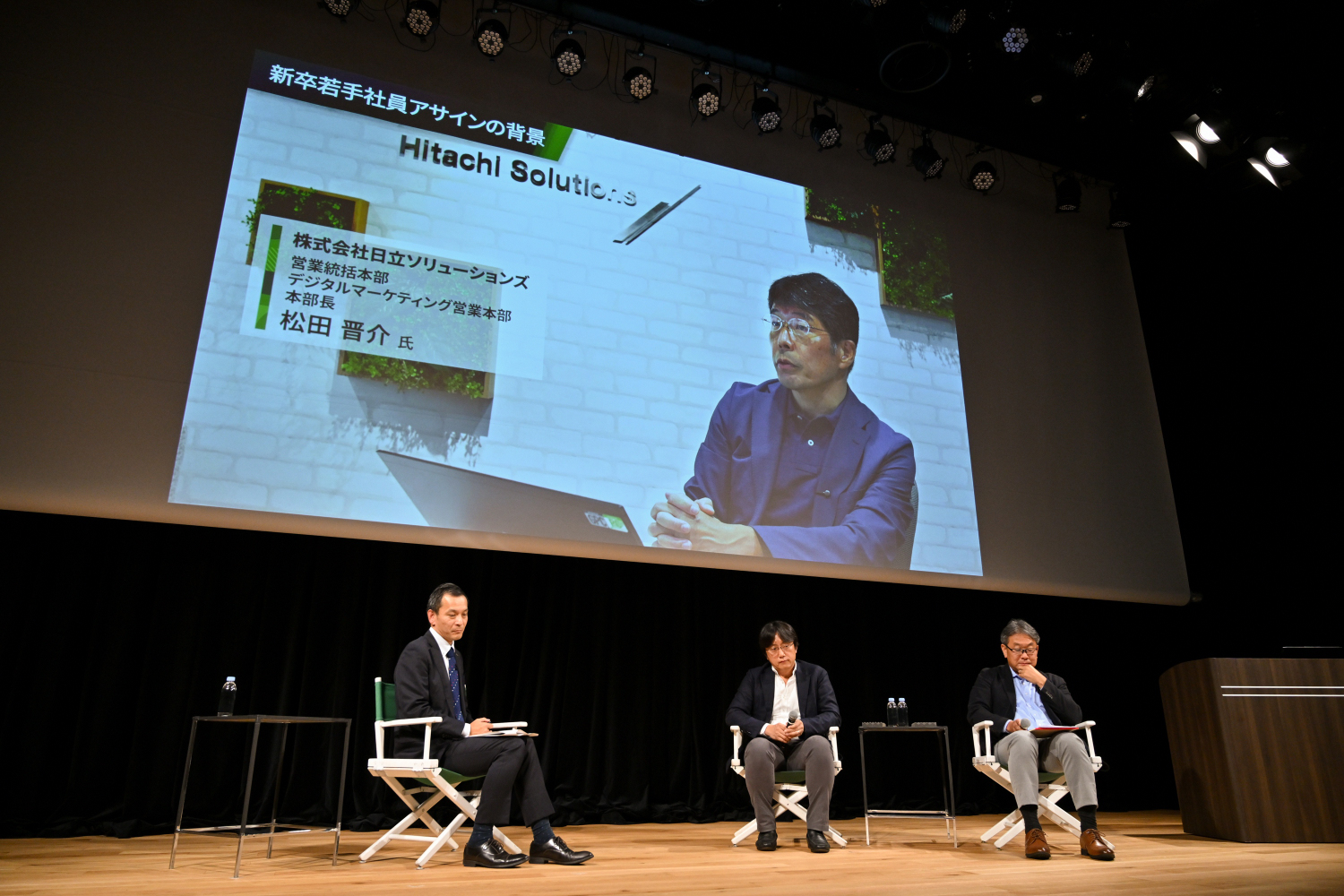 日立ソリューションズ松田氏のビデオ登壇とセッション会場の様子